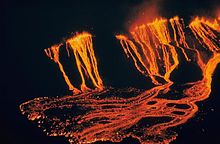 Une éruption volcanique avec des coulées de lave, vue la nuit.