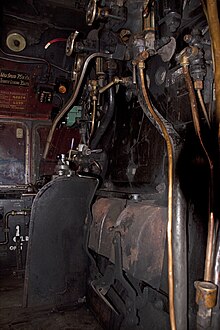 Kesselrückwand im Führerstand einer Dampflokomotive mit Feuertür und verschiedenen Armaturen