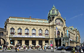 Un grand édifice Art nouveau, de couleur claire, au toit de cuivre et au corps central surmonté d'une grande fresque et d'un dôme.