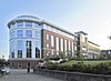 A four-story red-brick building with white accents on the left and top. Left end is rounded, park like area is on the left in front of the library building.