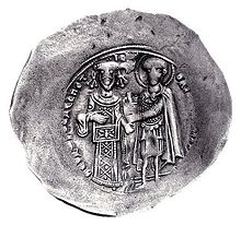 Round silver coin with two standing figures, the left one dressed in regalia and the right one as a warrior saint, handing a castle to the former