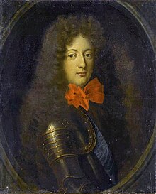 A young man in armor with a big red bow on his neck.