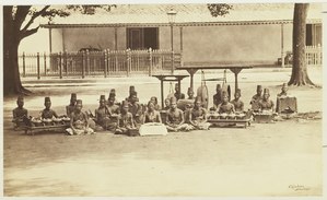 A Dalang (puppeteer), Sindhen (singer) and Wiyaga (gamelan musicians) with a Javanese gamelan at Keraton Yogyakarta, the sultan's palace in Yogyakarta c. 1885