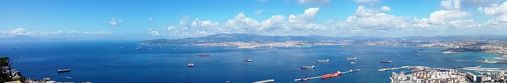 Maroko (sinistre, an la horizonto), Algeciras e La Linea (centre e dextre del imajo) e Gibraltar kun lua portuo (extreme dextre del imajo).