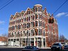 A five-story brick building with a turret, with a bright blue sky in the background