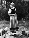 Blond tysk jente i dirndl, med to gutter som leker. Foto: NSDAPs rasepolitiske avdeling, etter 1933