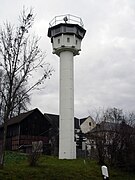 La torre blanca de altura de pie cerca de las casas y un granero; su base está formada por una columna redonda delgada, en la parte superior de las cuales es una cabina octogonal con ventanas-top colgado enfrentan en todas las direcciones; hay un foco de búsqueda en la parte superior de las torres de techo plano, y la barandilla alrededor del borde exterior del techo.