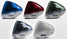 Side view arrangement of five iMacs, in clear dark blue, red, green, grey, and a frosted white.