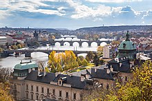 Une rivière au milieu d'une grande ville, traversé par plusieurs ponts, un bâtiment important au premier plan.