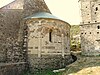 An ancient, round building projection faced in stone and featuring decorative arches and window