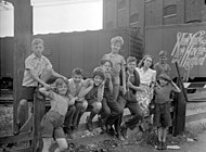 Entourée de neuf enfants du quartier Saint-Henri, devant un wagon, 1945.