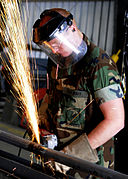 US Navy 100422-N-6357K-005 A Seabee grinds a pipe fitting to be used to fabricate a maintenance catwalk at a water treatment facility at Naval Station Rota, Spain.jpg