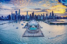 A photograph of Navy Pier, adjacent to Lake Michigan, in front of the Chicago skyline