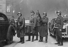 Blösche at right, 2nd from right is Heinrich Klaustermeyer; Jürgen Stroop at center, watching housing blocks burn during the Warsaw Ghetto Uprising. Picture taken at Nowolipie street looking East, near intersection with Smocza street. On the left burning balcony of the townhouse Nowolipie 66.