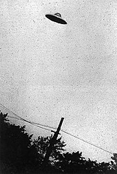 Photographie en noir et blanc d'une soucoupe volante aperçue dans le ciel.