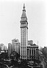 A streetscape of Madison Avenue and Madison Square Park showing the 48-story building of the Metropolitan Life Insurance Company Tower and the 1906 building of the Madison Square Presbyterian Church to its left