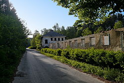 Silnice s cyklotrasou č. 241 v bývalé obci Jabloneček. V popředí je dnes již zbořená vojenská jídelna, vzadu je budova české školy.