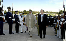 Two men walking between lines of armed soldiers in dress uniforms