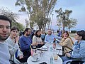 People sitting around a table outside near a large tree