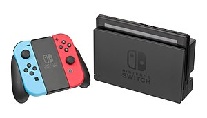 Farbige Variante der Joy-Con in der Joy-Con-Halterung, daneben die Nintendo Switch im stationären Modus