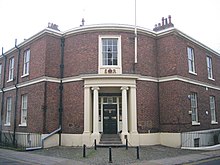 A Neogothic brick house with stone dressings and a curved porch on a street corner