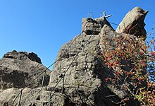 Vyhlídka na skalnatém vrchu Ořešníku, k níž vedou do skály vysekané schody opatřené zábradlím. Nad vyhlídkou je modré nebe.