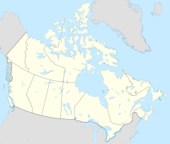 A yellow map of Canada, showing provincial and territorial booundaries, with a red dot in the northwestern section of the Northwest Territories