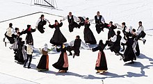 Un groupe de danseurs en costume breton traditionnel dansent en rond.