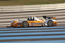 Photographie d'une voiture de sport-prototype blanche et jaune, vue de profile, sur une piste.