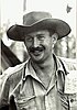 Informal portrait of grinning mustachioed man in wide-brimmed hat and military uniform