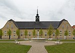 A church building, a frontal view. A park with a fountain in front of the church.