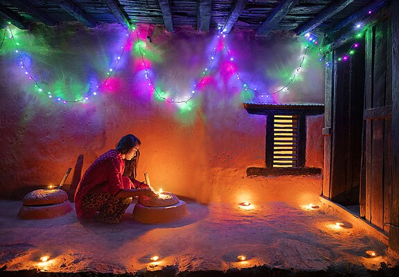 Religiosa nepalesa acendendo uma lamparina tradicional durante o festival Tihar. O Tihar é um festival hindu de cinco dias do Diwali comemorado no Nepal e nas regiões indianas de Siquim e Gorkhaland, que abrigam muitas etnias indianas gorkhas. O Tihar é marcado pelo acendimento de lamparinas dentro e fora da casa, mas, diferentemente do Diwali em outras partes da Índia, os cinco dias do Tihar incluem a celebração e a adoração das quatro criaturas associadas ao deus hindu da morte Iama, com o último dia reservado para as próprias pessoas. No calendário gregoriano, o festival ocorre em algum momento entre outubro e novembro de cada ano. (definição 5 983 × 4 153)