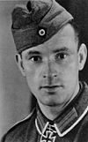 A man wearing a military uniform with an Iron Cross displayed at the front of his uniform collar.