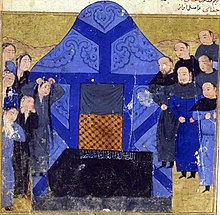 A number of mourners congregate on either side of a bright blue tent behind a coffin