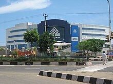 Front of large round building, with street and trees in front