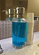 Blue mouthwash in dispenser with cups.jpg