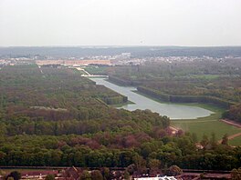 A river flowing through an urban area with greenery along the banks.