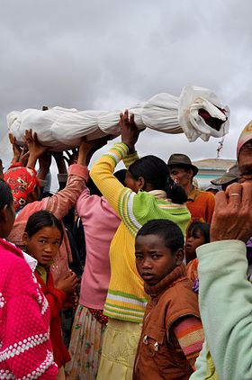 Famille portant le corps d'un de leurs ancêtres après avoir changé les linceuls