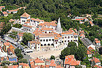 Aerial view of a castle with a white façade and orange roofs