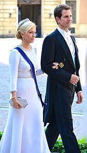 Photo d'un jeune couple ; l'homme porte un smoking noir et la femme une robe blanche.