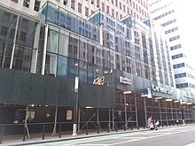 The glass annex to 1 Wall Street as seen from across Broadway. There is scaffolding in front of the annex.