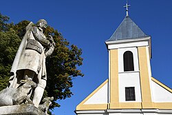 Szent Vendel szobra a római katolikus templom tornyával