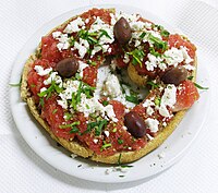 Dakos, traditional Cretan appetizer. Paximadi (hard bread) topped with fresh tomato, feta cheese, oregano, and olives drizzled with olive oil.