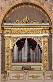 Tuyaux arrangés par taille ondulante dans un cadre doré richement ouvragé, l'ensemble sous un décor de voûte.