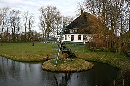 Tjasker Zuidschermer, met op de achtergrond de stolpboerderij