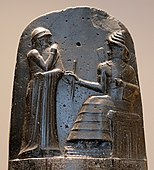 Hammurabi (standing), depicted as receiving his royal insignia from Shamash (or possibly Marduk). Hammurabi holds his hands over his mouth as a sign of prayer[92] (relief on the upper part of the stele of Hammurabi's code of laws).