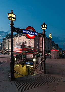 West entrance to the Piccadilly Circus tube station, early morning, blurred London bus in the background.