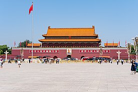 Groups of people wander around Tiananmen Square in the late afternoon. The eponymous Tiananmen, literally "Gate of Heavenly Peace", sits in the background.