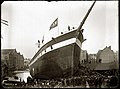 De tewaterlating in 1892 van een aan de Oostenburgervoorstraat gebouwd schip. Links zijn pakhuizen op Wittenburg te zien.