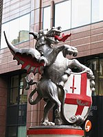 City boundary marker: a single dragon supporter holds the shield of arms